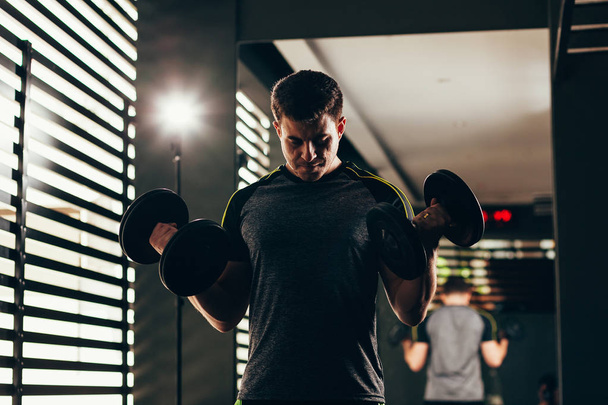Handsome man lifting dumbbell at gym. Workout concept - Fotografie, Obrázek