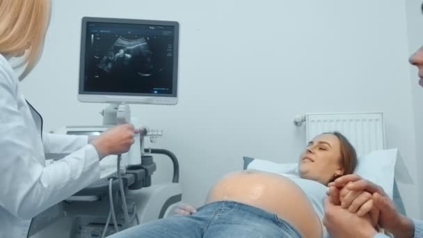 Close-up shot, in het ziekenhuis van de arts doet echografie te scannen naar een zwangere vrouw. Gynaecoloog bewegende transducer op de buik van de toekomstige moeder. - Video