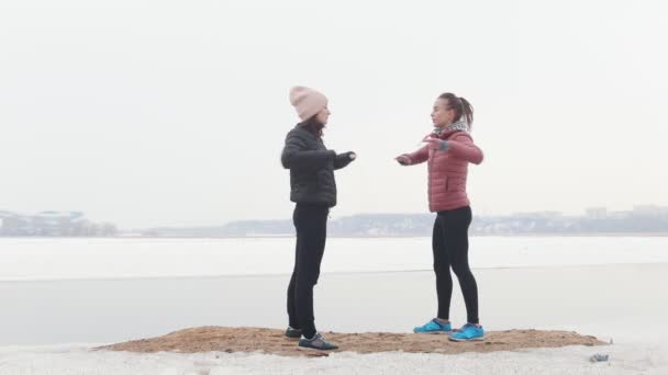 Duas mulheres magras a treinar na praia de neve. A aquecer
 - Filmagem, Vídeo