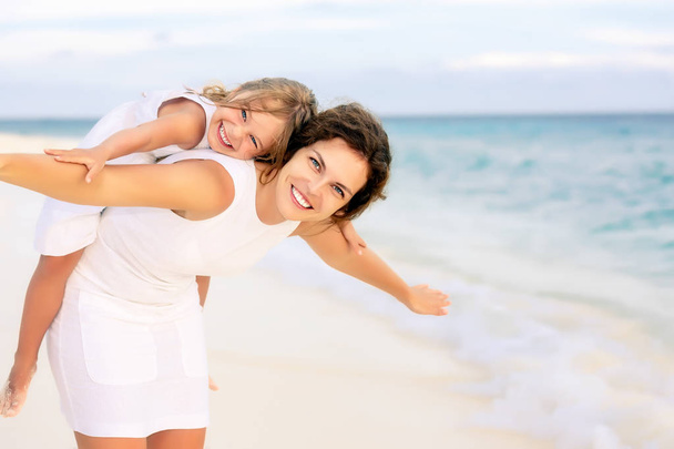 Happy mother and daughter on the ocean beach on Maldives at summer vacation - Фото, зображення