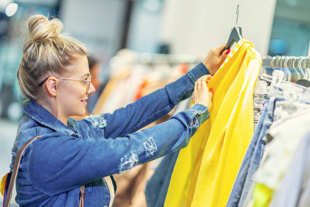 glückliche Frau kauft Kleidung im Geschäft ein - Foto, Bild