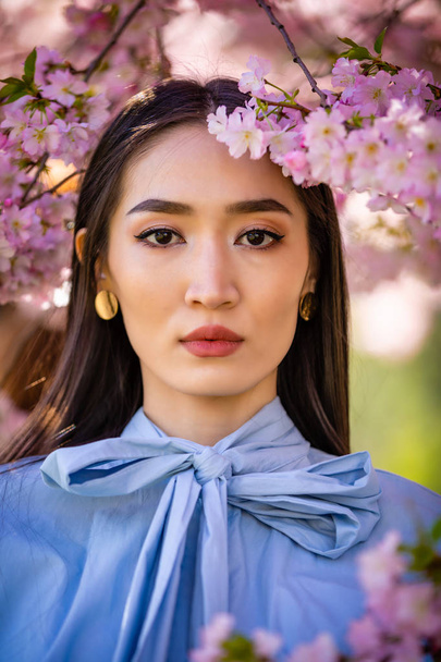 Beautiful young asian woman in blooming cherry blossoms garden - Photo, Image