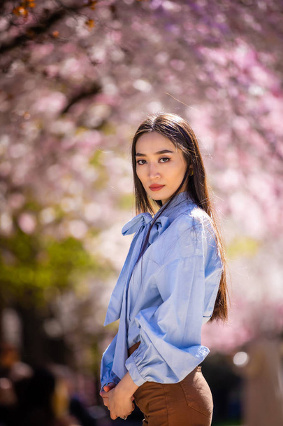 Beautiful young asian woman in blooming cherry blossoms garden - Foto, imagen