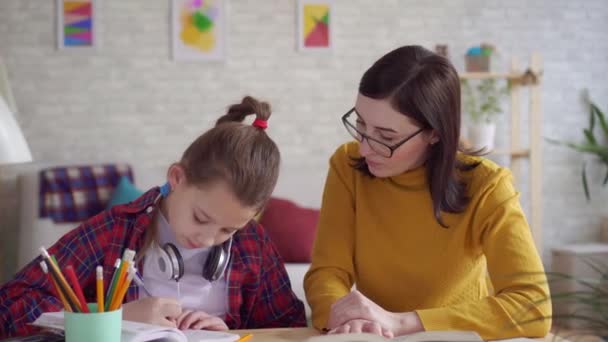 Close up mom helps daughter to do homework - Séquence, vidéo
