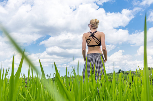 Relaxed healthy sporty woman enjoying in pure nature at beautiful green rice fields on Bali, Indonesia. - Fotó, kép