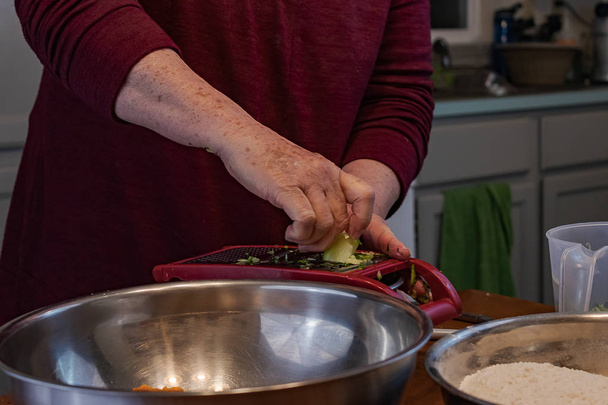 abuela trituración de calabacín con un rallador de queso
 - Foto, Imagen