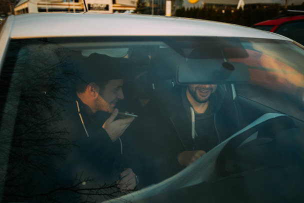 Ladrones sentados en un coche hablando por teléfono y planeando su
 - Foto, Imagen