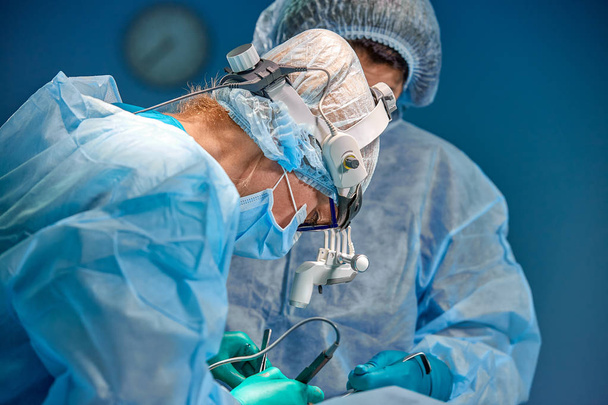 surgery, medicine and people concept - group of surgeons at operation in operating room at hospital - Photo, Image