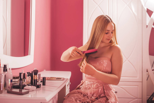 Tizenéves lány egy ruha, fésülködés a haját, a hálószobában - Fotó, kép