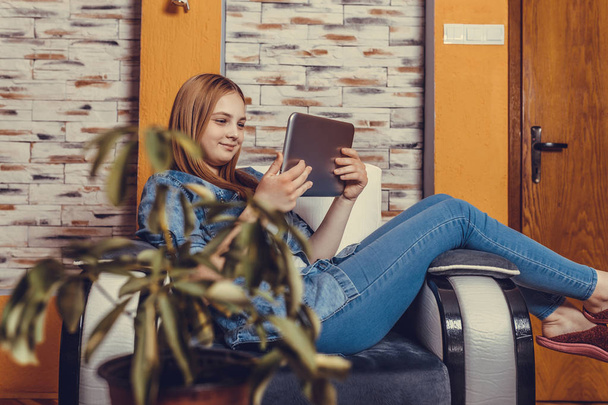 Молодая красивая девочка-подросток сидит с планшетом дома, учится
 - Фото, изображение