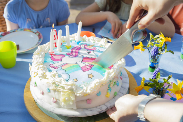 Cutting a birthday cake with an unicorn character - Zdjęcie, obraz
