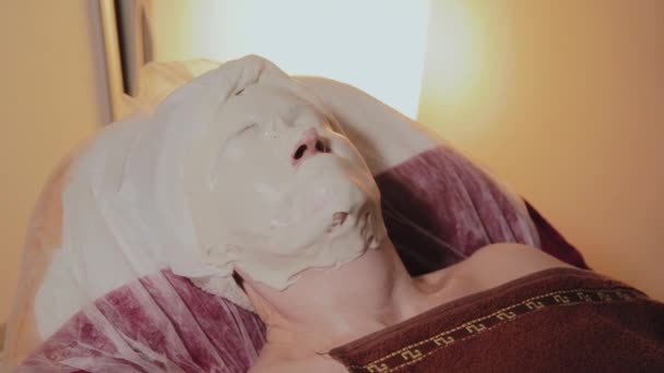 Goed verzorgde oudere vrouw draagt een masker op de procedure in een schoonheidssalon. - Video