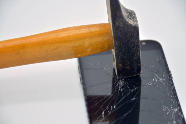 Сломанный экран мобильного телефона с молотком
 - Фото, изображение