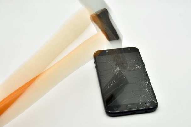 Сломанный экран мобильного телефона с молотком
 - Фото, изображение