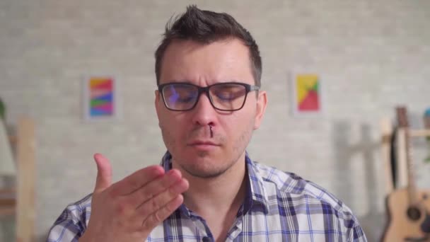 Πορτρέτο ενός νεαρού άνδρα με γυαλιά που έχει αίμα από τη μύτη του αργή mo - Πλάνα, βίντεο