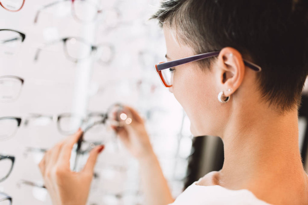 Beautiful middle age woman choosing a glasses in optician store. - Foto, Imagem
