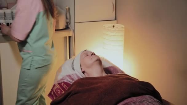 Un esthéticien professionnel prépare le visage d'une femme âgée pour l'intervention. Innovations cosmétologiques
 - Séquence, vidéo