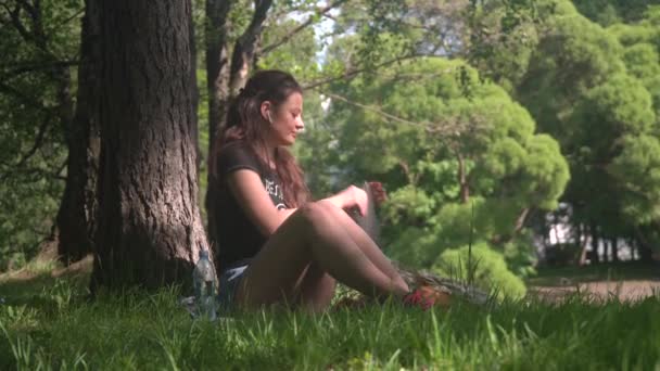 Young woman student uses digital tablet in park - Záběry, video