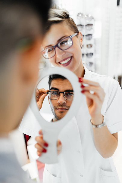 Young optometrist helps customer to choose right eyeglasses - Valokuva, kuva