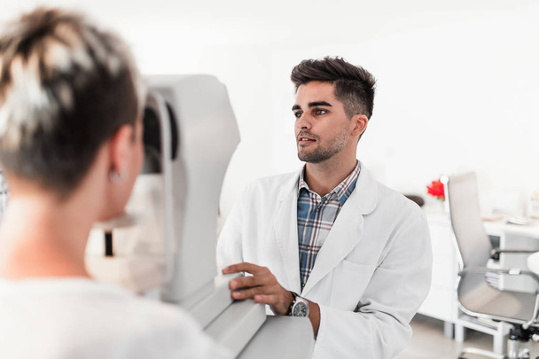 Male optometrist checking patient's vision at eye clinic. Medical examination. - Valokuva, kuva