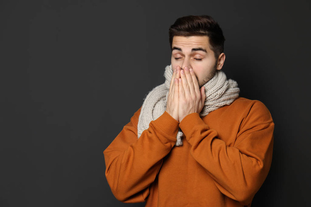 Handsome young man coughing against dark background. Space for text - Фото, изображение