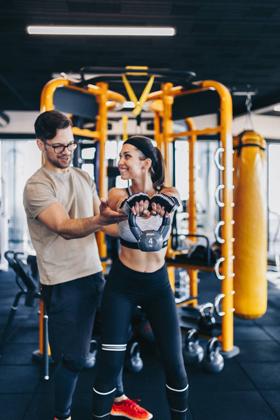 Young fit and attractive man and woman exercising workout with kettlebell in modern fitness gym. - Foto, immagini