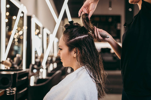 Beautiful brunette woman with long hair at the beauty salon getting a hair blowing. Hair salon styling concept. - Foto, imagen