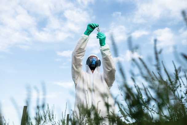 Weed control. Industrial agriculture researching. Man in protective suite and mask taking weed samples in the field. Natural hard light on sunny day.  - Φωτογραφία, εικόνα