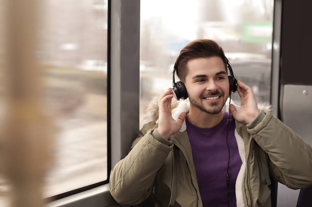 Mladý muž poslouchá hudbu se sluchátky ve veřejné dopravě - Fotografie, Obrázek