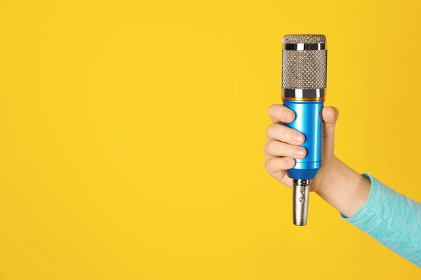 Child holding microphone on color background, closeup of hand. Space for text - Fotografie, Obrázek
