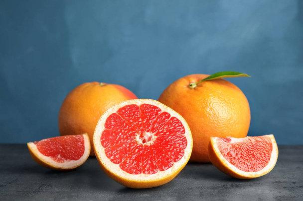 Fresh tasty grapefruits on table against color background - Фото, зображення