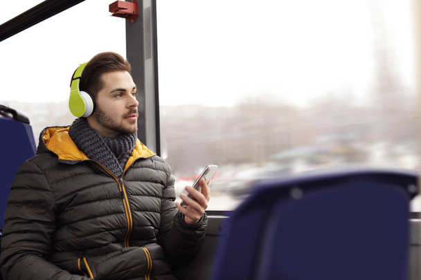 Young man listening to music with headphones in public transport - Photo, Image