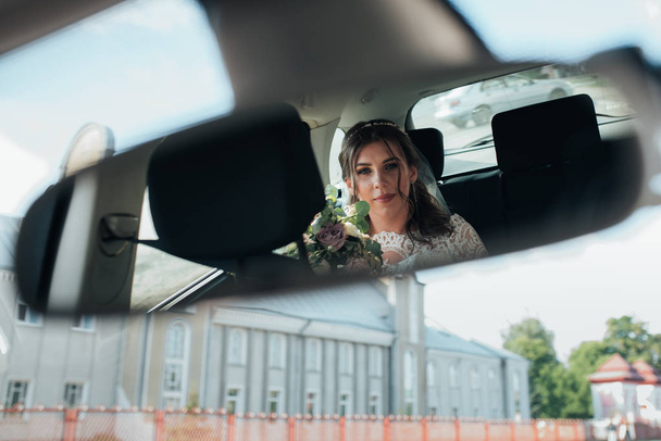De reflectie van de bruid in de achteruitkijkspiegel van de auto - Foto, afbeelding