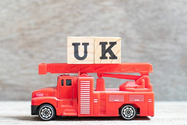 Red Fire Truck trzymać blok listu w słowie UK (skrót od Zjednoczonego Królestwa) na tle drewna - Zdjęcie, obraz