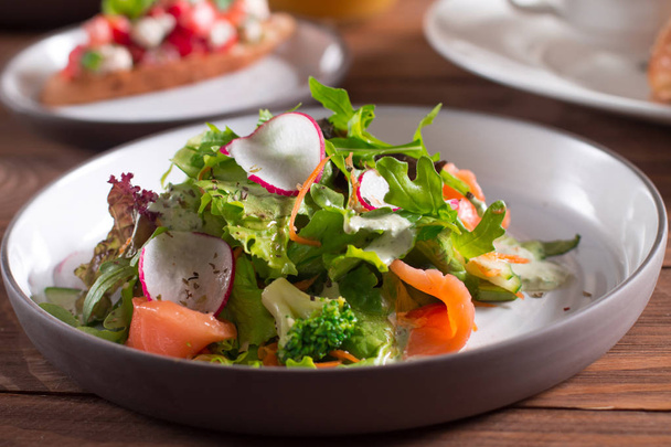 Mediterranean cuisine. Salad. Slices of salmon with fresh vegetable salad on a plate. - Foto, Imagem