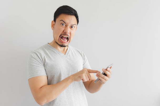 Angry man in grey t-shirt get mad on the smartphone. - 写真・画像