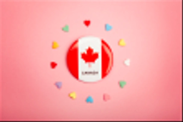Ευτυχισμένος ημέρα του Καναδά ευχετήρια κάρτα με καναδική σημαία στο κέντρο μέσης και πολλές καραμέλες πολύχρωμες καρδιές γύρω από το σχετικά ζουν κοραλλιών ροζ φόντο. Πολυπολιτισμικότητα εθνικών αξιών έννοια. - Φωτογραφία, εικόνα
