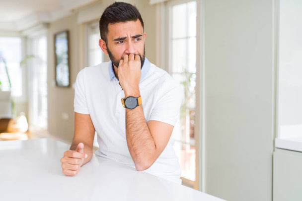 Pohledný Hispánec s bílým tričkem doma ve stresu a nervózní s rukama na ústech. Úzkostná potíž. - Fotografie, Obrázek
