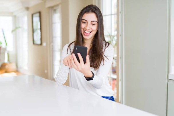 Jovem mulher usando smartphone, sorrindo mensagens de texto felizes e digitação
 - Foto, Imagem