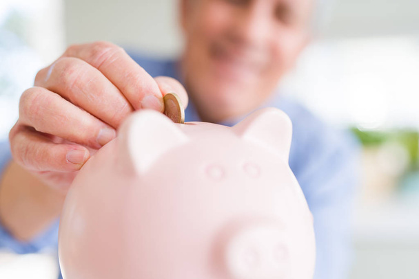 Mann steckt eine Münze in Sparschwein, als Sparkassenangestellte lächelt - Foto, Bild