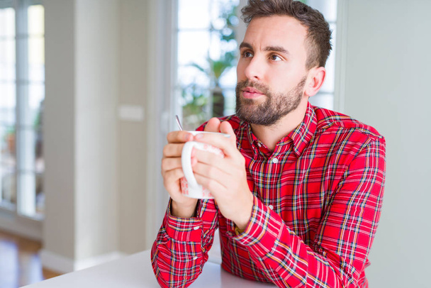 Handsome man drinking a cup of coffee at home - Photo, Image