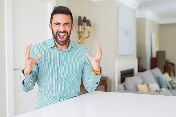Handsome hispanic man at home crazy and mad shouting and yelling with aggressive expression and arms raised. Frustration concept. - Foto, Imagen