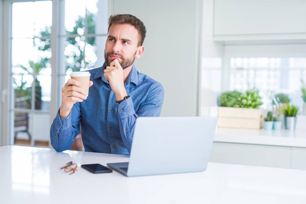 Pohledný muž pracovat pomocí přenosného počítače a pít šálek kávy vážná tvář přemýšlet o otázku, velmi zmaten myšlenku - Fotografie, Obrázek