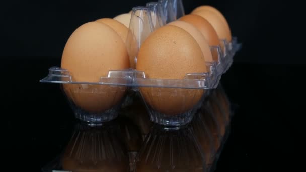 Suuret ruskeat kananmunat läpinäkyvällä muovitarjottimella valkoisella taustalla
 - Materiaali, video