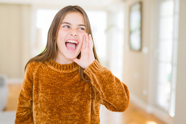Beautiful young girl kid at home shouting and screaming loud to side with hand on mouth. Communication concept. - Foto, Bild