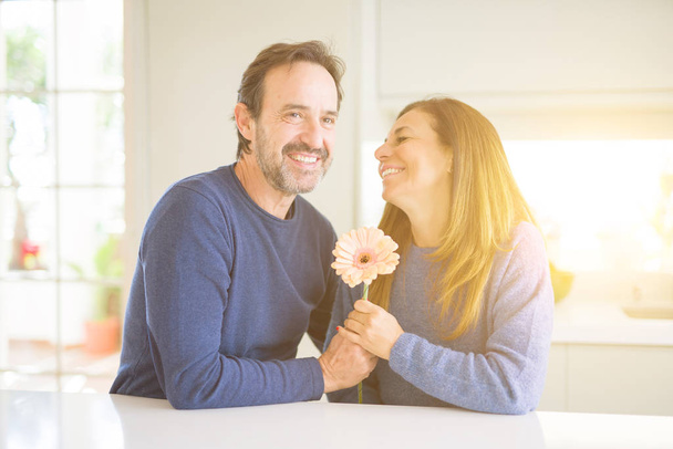 Romántica pareja de mediana edad sosteniendo flores enamoradas en casa
 - Foto, Imagen