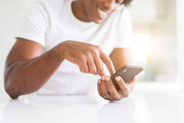 Κοντινό πλάνο του χέρια αφρικανική αμερικανική άνθρωπος που χρησιμοποιούν smartphone και smil - Φωτογραφία, εικόνα