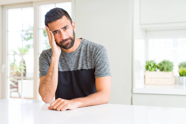 Handsome hispanic man wearing casual t-shirt at home thinking looking tired and bored with depression problems with crossed arms. - Fotografie, Obrázek