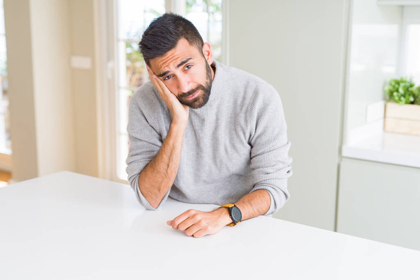 Hombre hispano guapo usando suéter casual en casa pensando que se ve cansado y aburrido con problemas de depresión con los brazos cruzados
. - Foto, imagen