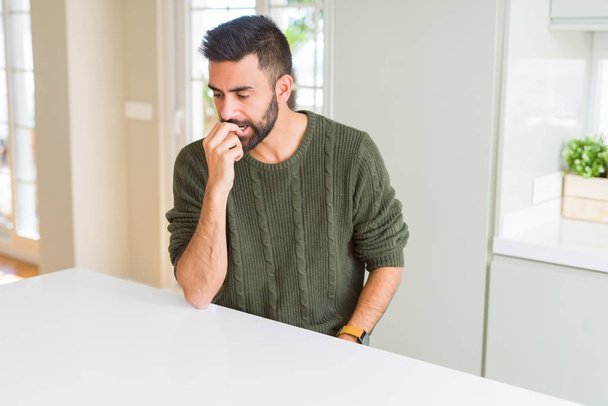 Handsome hispanic man wearing casual sweater at home looking stressed and nervous with hands on mouth biting nails. Anxiety problem. - Fotoğraf, Görsel
